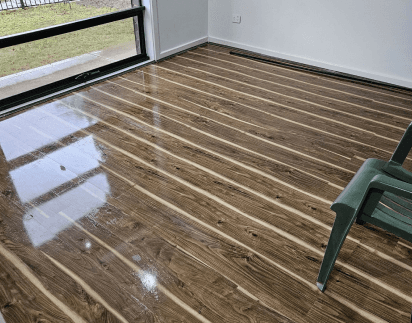 Buffed hardwood floor in an empty living room after a deep clean