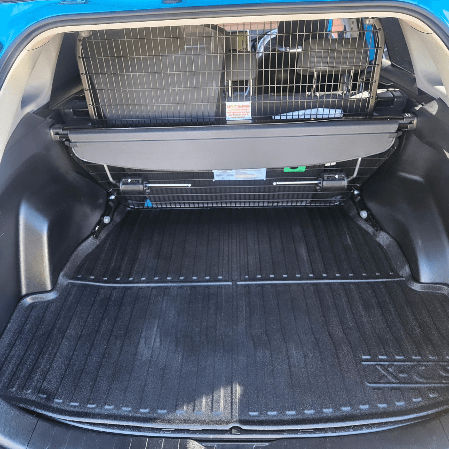 Detailed cargo area of a blue SUV with a fitted boot liner and cargo barrier