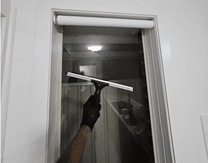 Cleaner squeegeeing a shower screen until the glass is streak-free