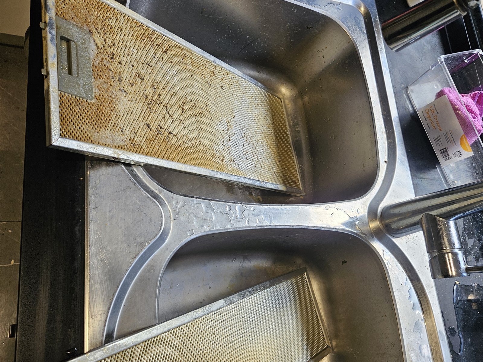 Kitchen sink with greasy range hood filters before cleaning